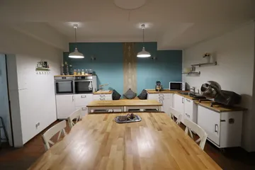 Küche mit Holztisch, elektrische Geräte und blaue Wand.