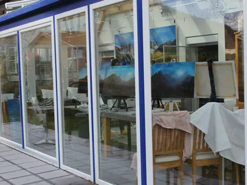A studio shows painted landscapes behind glass.