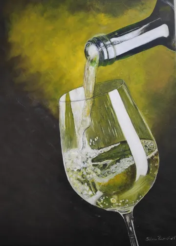 A bottle pours sparkling wine into a glass.