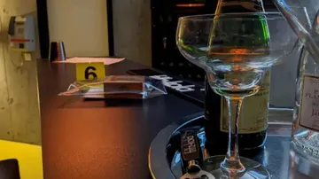 Glass on bar counter surrounded by bottles and decoration