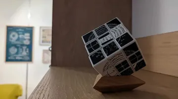 Cube balanced on a wooden base in a modern room.