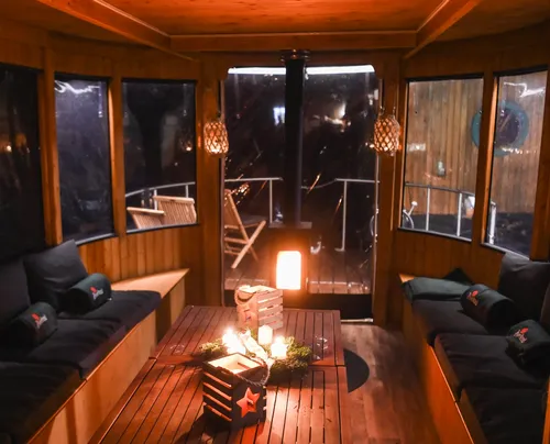 Holzhütte mit einem Tisch, Kerzen brennen, gemütlich eingerichtet.