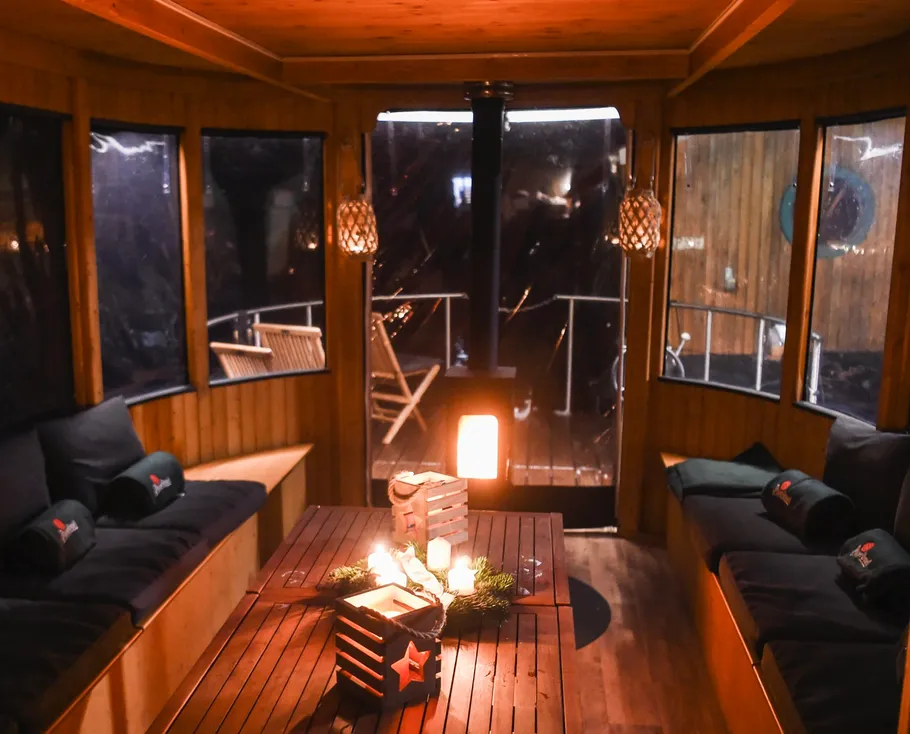 Holzhütte mit einem Tisch, Kerzen brennen, gemütlich eingerichtet.