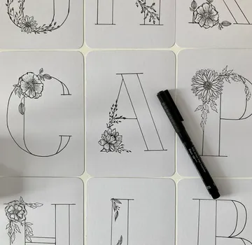 Schöne Buchstaben mit floralen Mustern, daneben ein Marker.