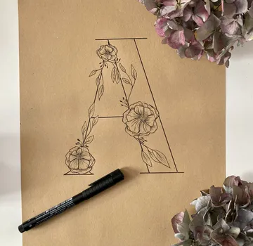 Flowers decorate the letter A on brown paper.
