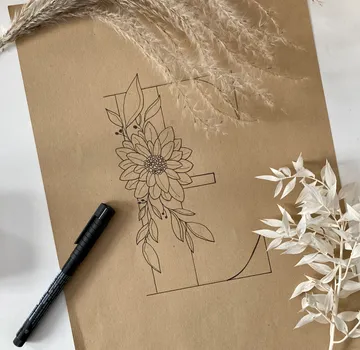 Schwarzer Stift zeichnet florales Motiv auf braunem Papier.