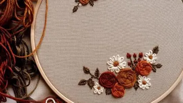 Embroidery frame with colorful floral motifs on a fabric background.