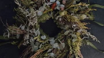 Kranz aus getrockneten Pflanzen auf dunklem Hintergrund.