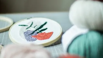 Embroidered frame features colorful plant patterns surrounded by thread.