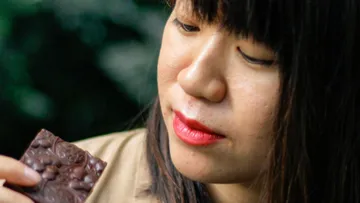 Woman holding chocolate and concentrating on it.