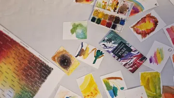Papier mit Aquarellfarben liegt auf einem Tisch.