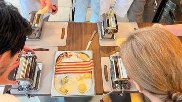 Dough is processed by pasta machines in a kitchen.