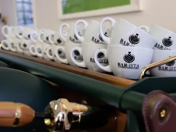 Cups sit neatly on a wooden counter in a cafe.