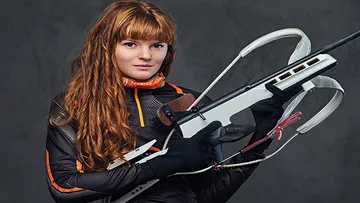 A woman is holding a crossbow in sporty clothes.