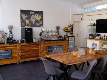 Wooden table, chairs, coffee makers; quiet, inviting coffee place.