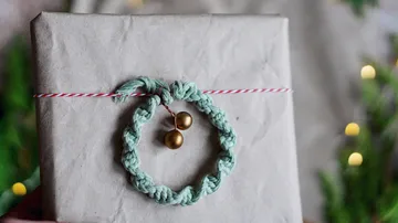 Geschenk eingewickelt mit grünem Band und goldenen Glocken.