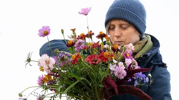 Woman holding colorful bouquet of flowers in cool surroundings.