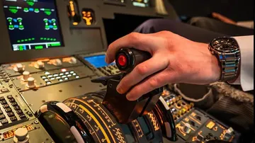 A pilot controls an aircraft lever in the cockpit.