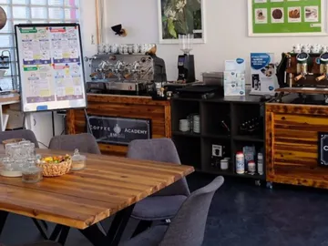 Table with snacks, coffee machines and training materials in a café.