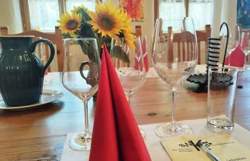Table setting with glasses, flowers and red napkins.