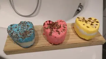 Drei bunte Herzen auf Holzbrett in Badumgebung.
