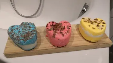 Herzförmige Badebomben liegen auf einem Holzbrett.