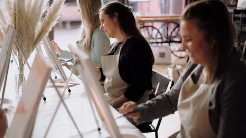 Students paint on easels in a creative space.
