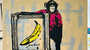 Monkey stands next to a frame with a banana.