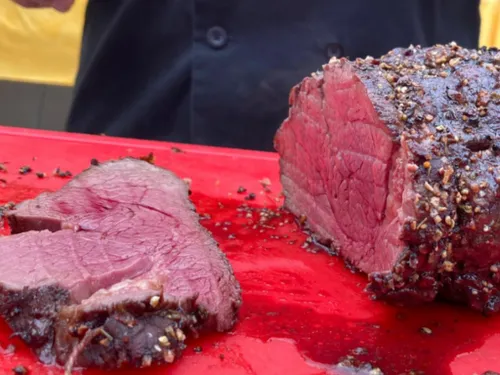 Piece of beef on red cutting board, freshly sliced.