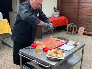 Koch bereitet Lachs auf einem Tisch in der Küche vor.