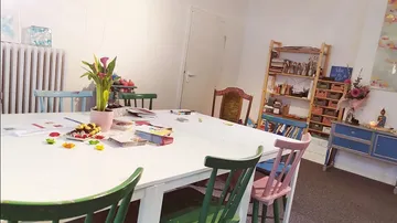 Ein Tisch mit bunten Stühlen in einem kreativen Raum.