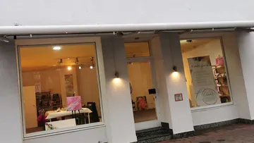 Kunstgalerie zeigt bunte Gemälde, helle Beleuchtung innen.