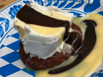 Dessert auf einem Teller, mit Sahne, Soße und Kuchen.