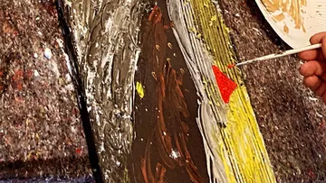 Colored brush paints red on a wooden surface.