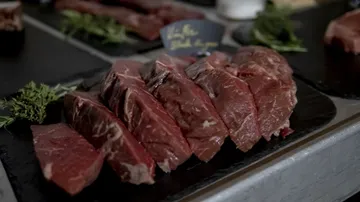 Frisches Fleisch liegt auf einem schwarzen Brett, dekoriert.
