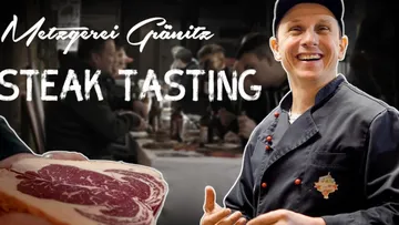 Meat piece is presented; gourmet event in a cozy setting.