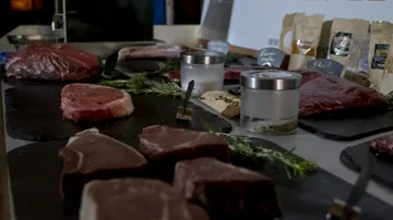 Pieces of meat lie on plates surrounded by spices.