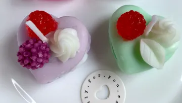 Herzförmige Süßigkeiten dekoriert mit Sahne und Früchten.