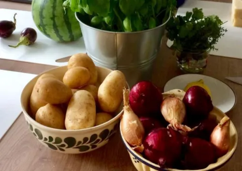 Bowls of potatoes and red onions on table.