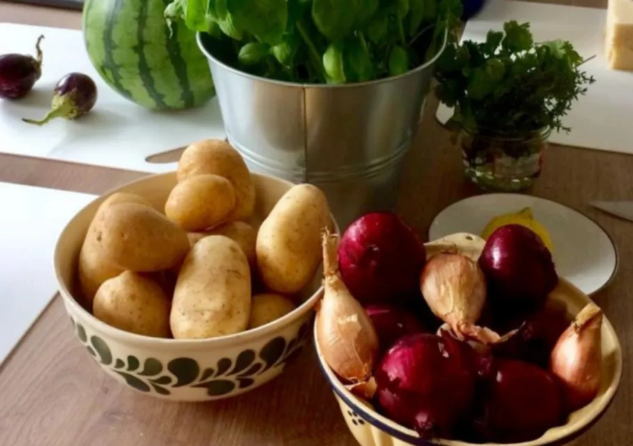 Bowls of potatoes and red onions on table.