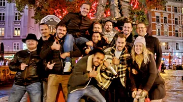 Group of men and a woman pose happily at night.