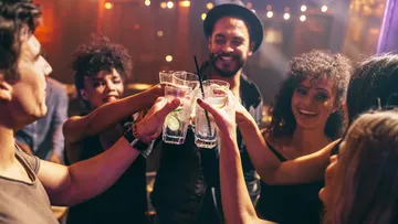 Friends toast with glasses in a festive setting.