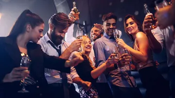 Young people party, toast with drinks in a nightclub.