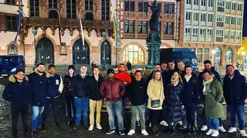 Gruppe von Menschen posiert vor einem historischen Gebäude.