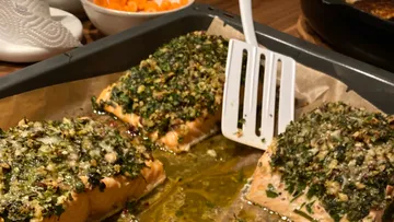 Salmon fillets with herb crust on a tray, cooked.