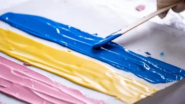 Farben werden mit einem Spatel auf eine weiße Oberfläche aufgetragen.