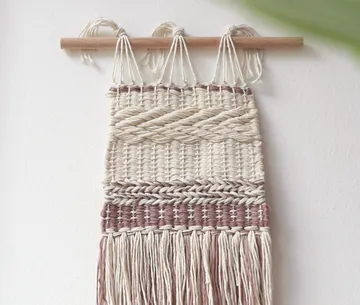 Wandbehang hängt, aus geflochtenem Material, an einer Wand.
