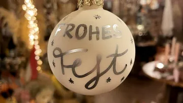Christmas tree ball with the word “HAPPY HOLIDAYS” hangs decoratively.