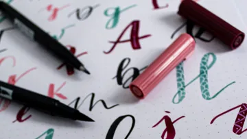Stifte liegen auf einem Blatt mit bunten Buchstaben.