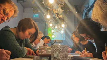 Gruppenteilnehmer zeichnen konzentriert unter dekorativen Lampen.